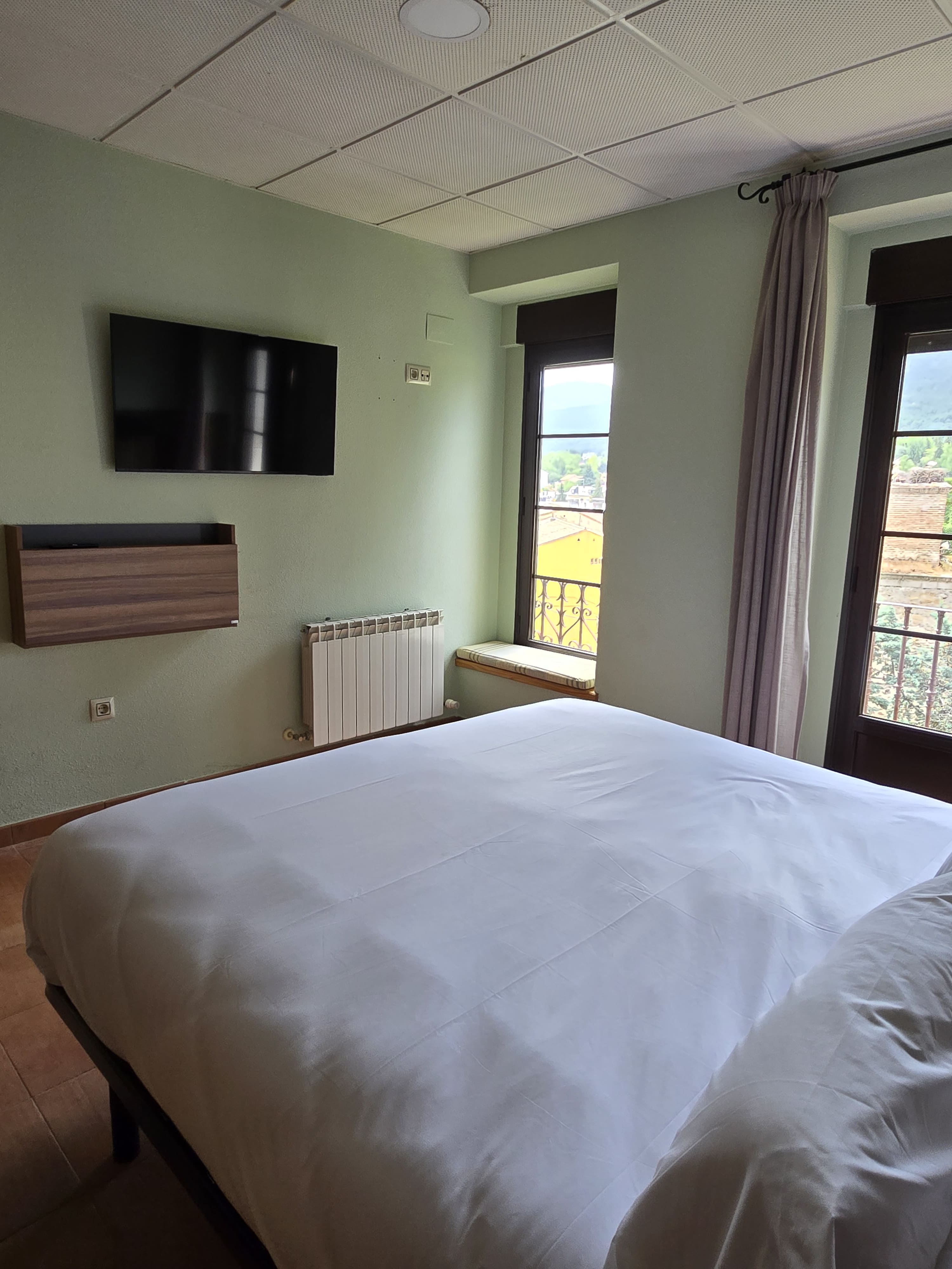 Cama matrimonial con balcón y vistas a la sierra en habitación doble estándar